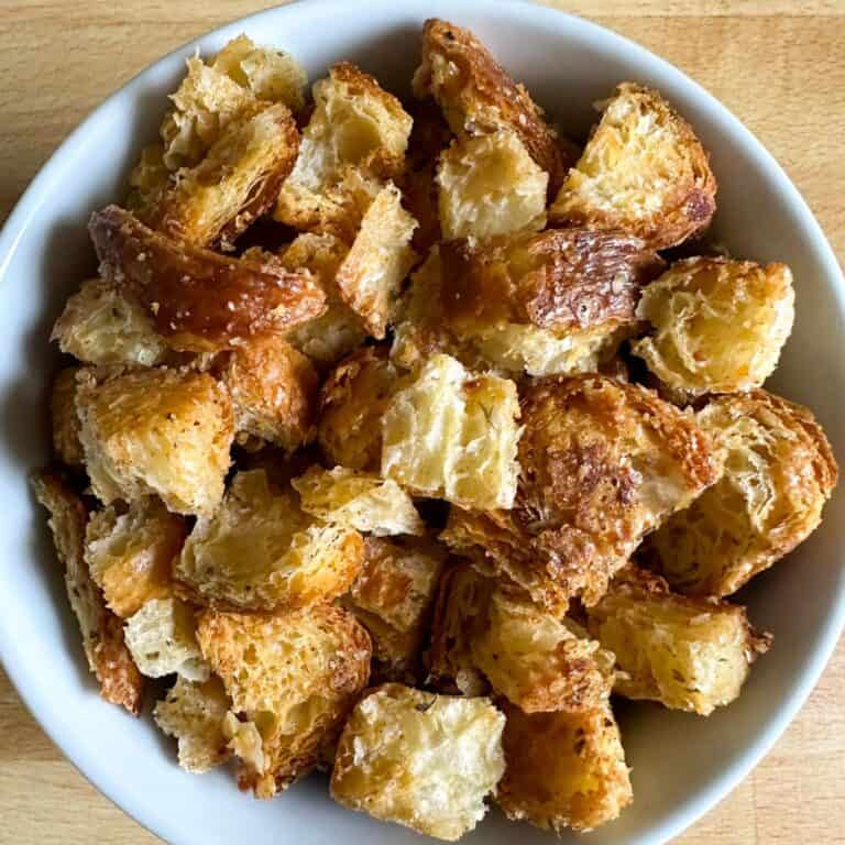 A white bowl full of homemade croissant croutons.