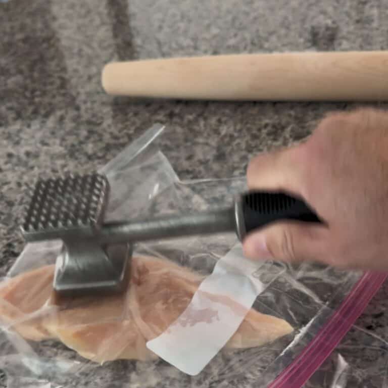 Demonstrating how to flatten chicken breast by pounding with a mallet