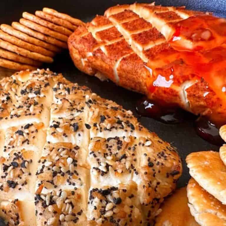 Two blocks of smoked cream cheese, one with bbq rub and the other with everything bagel seasoning, some crackers in the background