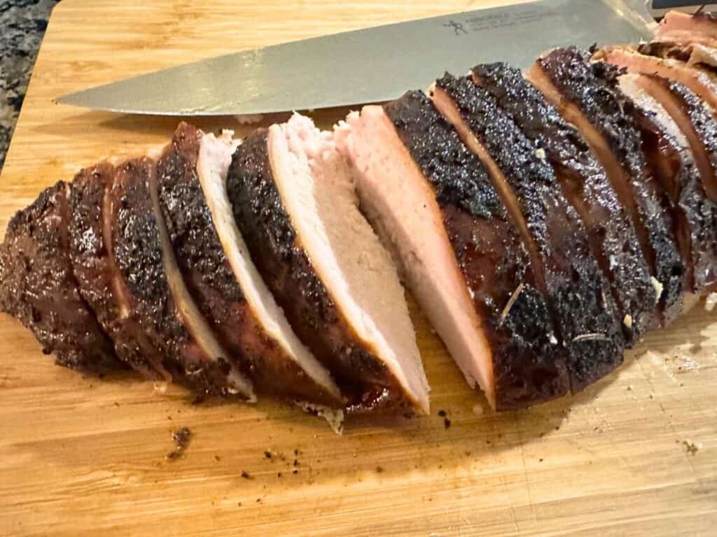 Smoked turkey breast sliced on a wooden cutting board