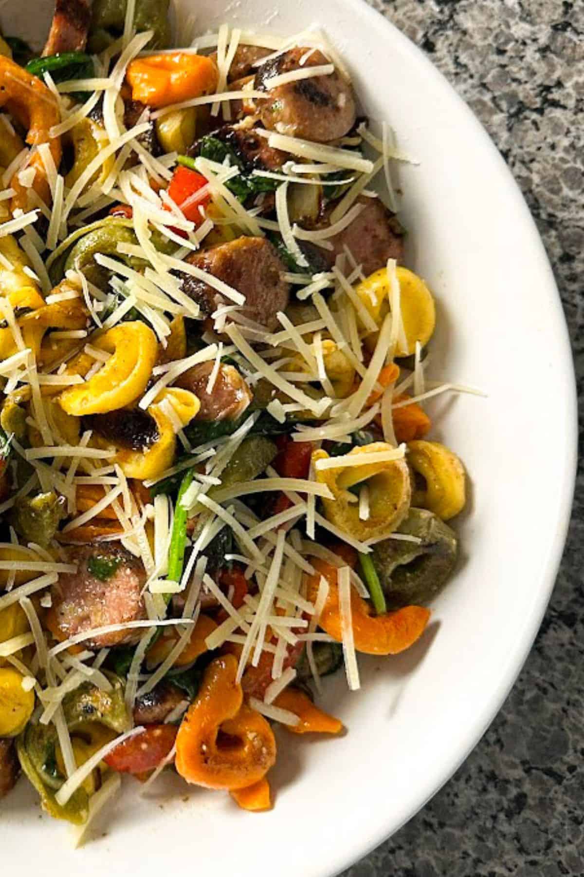 White plate loaded with Blackstone tortellini with sausage and veggies