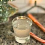 A polar bear shot in a shot glass with a candy cane in the background