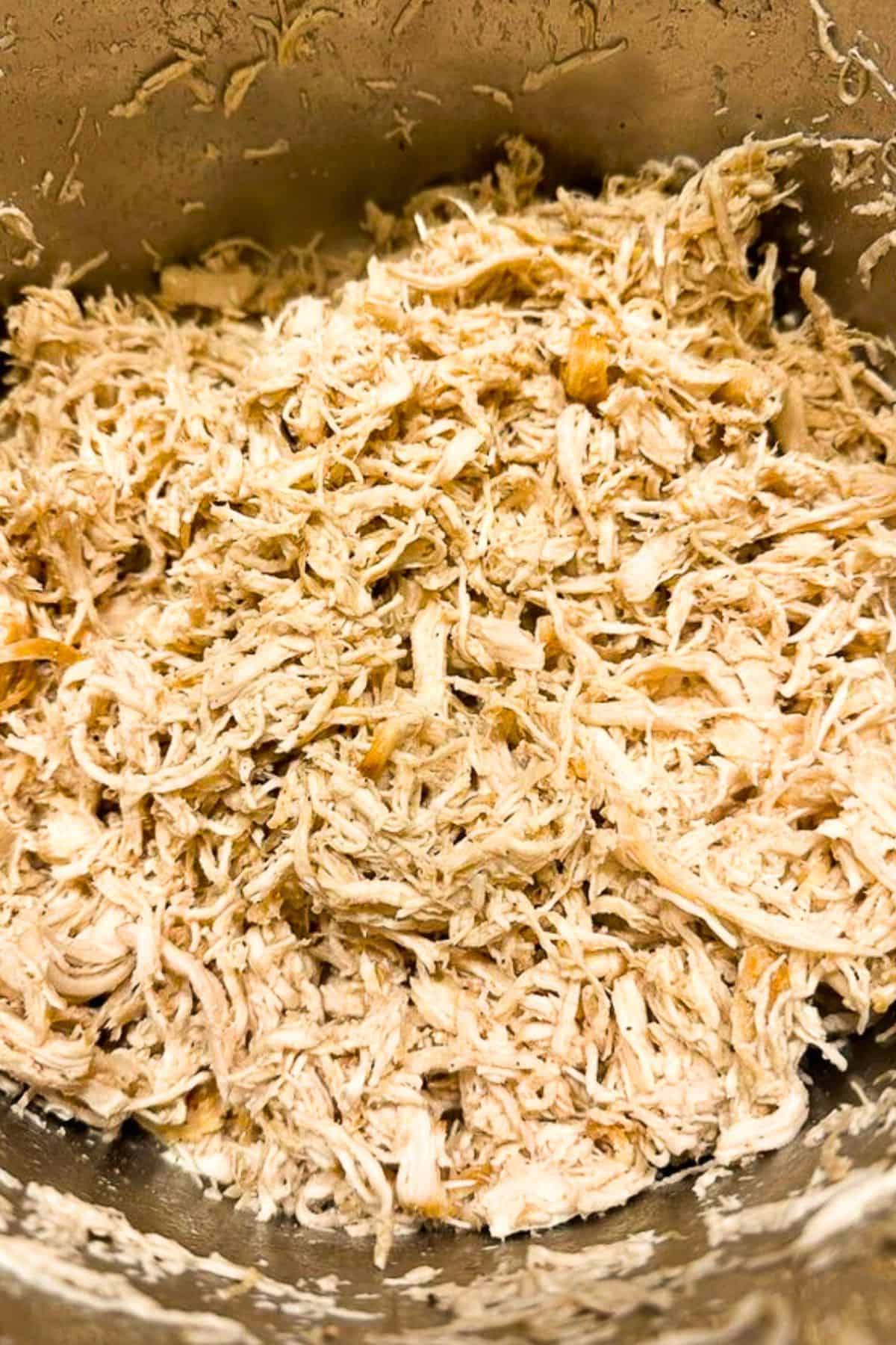 Aluminum mixing bowl full of shredded chicken