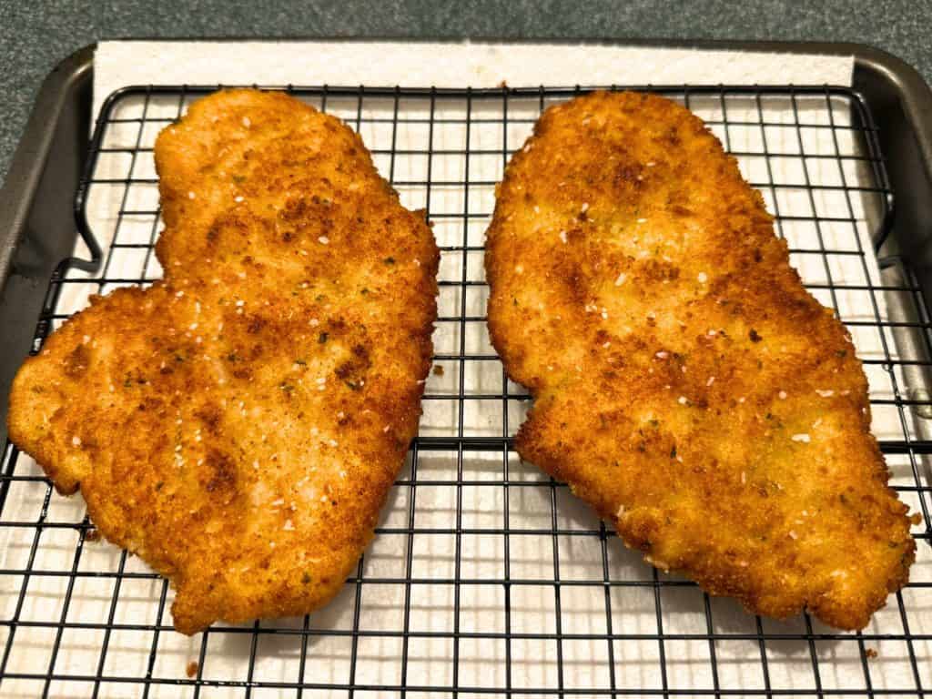 Chicken cutlets resting on a wire rack