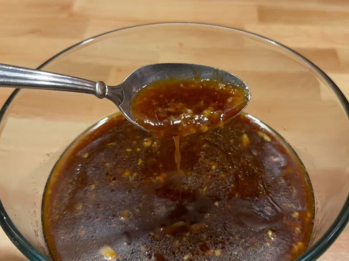 A bowl full of homemade honey soy marinade, and a spoon drizzling it
